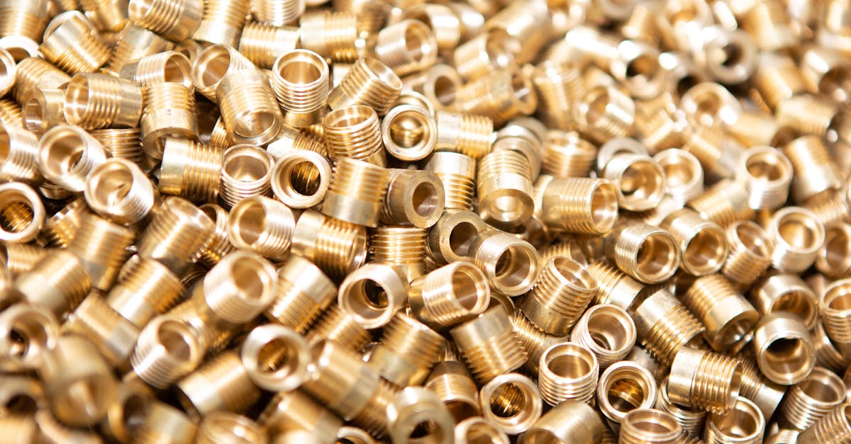 a detailed close up of a pile of brass screws and nuts with a golden metallic finish